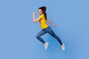 Time To Move. In Motion Portrait Of Happy Asian Girl Jumping In The Air Over Purple Background, Full-Length Shot With Copy Space photo
