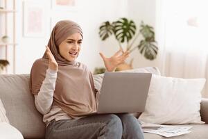 Computer problems. Angry arab woman having issues with laptop at home, annoyed of bad internet connection, free space photo