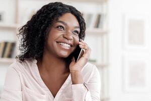 Modern Communication. Joyful black woman with braces talking on cellphone at home, enjoying pleasant conversation, copy space photo