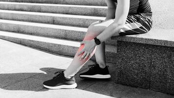 Leg injury while jogging. Guy with expression of pain on face, sits and rubs leg on street, free space photo
