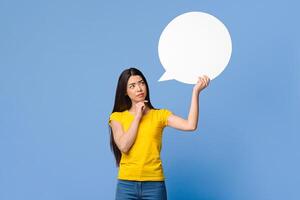 Let Me Think About It. Doubtful Asian Girl Holding And Looking At Empty Speech Bubble, Having Difficult Choice, Standing Over Purple Background photo