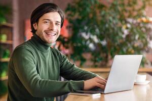 Freelance concept. Cheerful man programmer working at cafe, enjoying his job, copy space photo