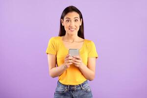 Surprised positive lady using smartphone device, chatting online, typing sms, glad to recieve many messages of congratulation on mailbox, looking overjoyed at camera, connected to wireless internet photo