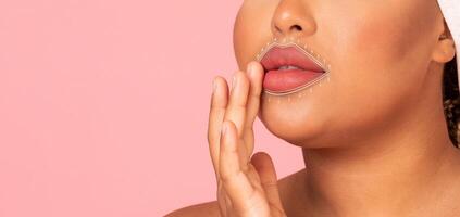 A woman enjoys a facial massage focused on rejuvenation and anti-aging techniques, enhancing her skin care routine. The soft pink background adds warmth to the pampering experience, copy space photo