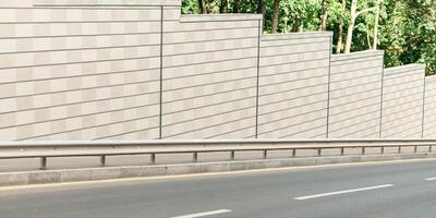 Modern road in city near big green park. Amazing view of empty highway in town street with gray stone walls on sides and with pedestrian sidewalk in summer sunny day, anyone, free space, outdoor photo