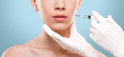 Cropped of woman getting lip injection over grey studio background, panorama photo
