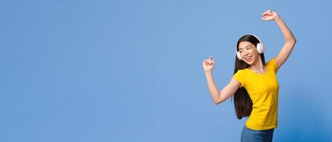 Joyful Korean Girl Dancing While Listening Music In Wireless Headphones, Standing Over Purple Studio Background, Panorama With Copy Space photo