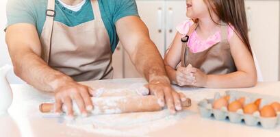 Joyful Father And Daughter Baking Pastry Together Rolling Out Dough In Kitchen At Home. Selective Focus photo