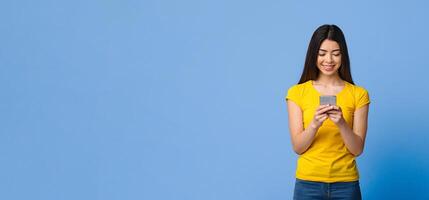 Cool App. Happy asian girl using smartphone, texting with friends while standing over purple studio background, copy space photo