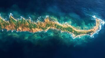 This aerial perspective displays a unique coastal landform, highlighting the interplay between land and ocean in a remote area. The vivid colors illustrate various vegetation and water depths. photo