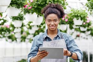 Digital technology in farm management. Smiling african american girl control work of greenhouse using tablet, free space photo