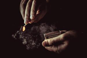 Playing with fire. A burning match in a man's hand on a black background. photo