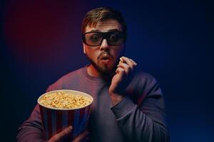 A man in 3D glasses and popcorn is watching a movie. photo