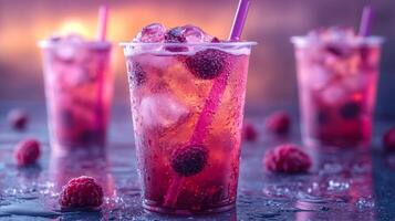 Three transparent cups filled with refreshing raspberry beverages sit on a table. Ice cubes and raspberries float atop the drinks, while colorful straws add a playful touch. photo