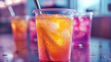 Brightly colored drinks filled with ice sit in clear plastic cups on a shiny surface. The atmosphere is lively, with hints of celebration and refreshment in the air. photo