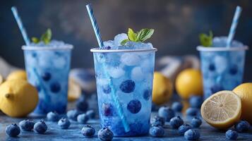 Bright blueberry lemonade drinks filled with ice and fresh blueberries are served in clear cups. Lemon slices and mint leaves add freshness to a vibrant summer atmosphere. photo