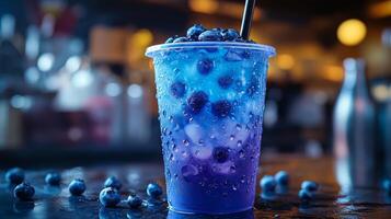A vibrant blueberry drink with ice and blueberries is placed on a bar counter. The dimly lit background enhances the colorful layers of the beverage, creating an inviting atmosphere. photo