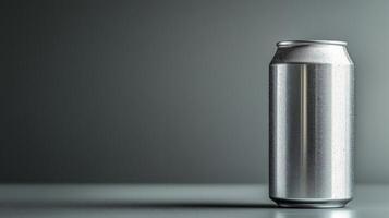 A shiny silver can stands upright on a smooth surface, illuminated by soft light against a plain dark backdrop, highlighting its sleek design and metallic finish. photo