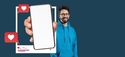 A smiling influencer holds a smartphone with a blank screen showcasing a social media application. The blue background enhances the focus on the phone and messaging elements. photo