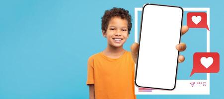 African American boy young influencer smiles while holding a blank smartphone, ready for social media activity. Colorful chat bubbles with hearts emphasize the excitement of online connections photo