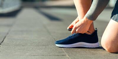 Get ready for training. Guy tying laces on sneakers at stadium, cropped, close up, free space photo