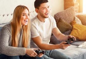 A couple joyfully engages in a gaming session, sharing laughter and excitement. They sit comfortably on a sofa surrounded by soft cushions, soaking in the warm light from the window. photo