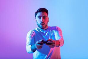A young man expresses surprise while playing a game, holding a controller. Colorful blue and purple lighting enhances the excitement of the gaming experience. photo