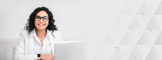 Successful Business Woman. Excited latin lady sitting at desk, smiling and looking at camera at modern office, copy space photo