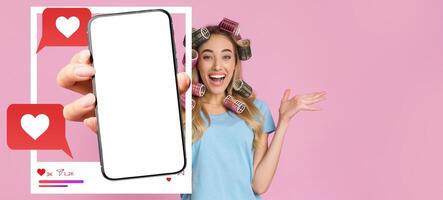 An influencer with hair rollers excitedly presents a smartphone screen with a blank interface, emphasizing social media interactions like chatting and sharing within a vibrant background. photo