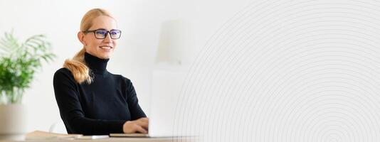 A woman with glasses is sitting at a desk in a stylish office, focused on her laptop. The bright room features minimalistic decor and lush green plants, creating a calming atmosphere, copy space photo