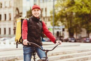 Courier Service. Delivery Guy On Bicycle Smiling To Camera Posing With Bike In City Outdoors. Empty Space For Text photo
