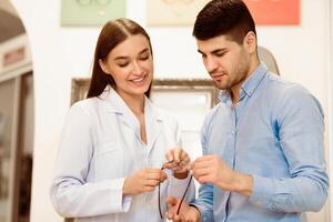 A friendly optometrist helps a man select a pair of stylish eyeglasses in an elegant optical store. The interaction showcases expert guidance and personal attention in a welcoming environment. photo