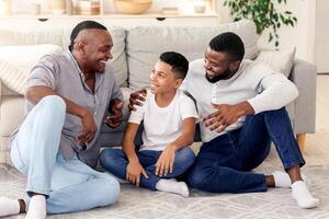 A grandfather, father, and son share laughter and stories in a warm and inviting living space, highlighting meaningful family connections and joyful interactions. photo
