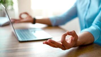 A young Arab entrepreneur sits at a desk in an office, practicing mindfulness with a calm demeanor. His laptop is open while he focuses on his breathing in a professional setting. photo