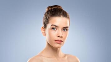 Portrait of beautiful caucasian woman posing topless over gray studio background. Young pretty naked lady with smooth skin looking at camera, copy space. Youth, rejuvenation, anti-aging concept photo