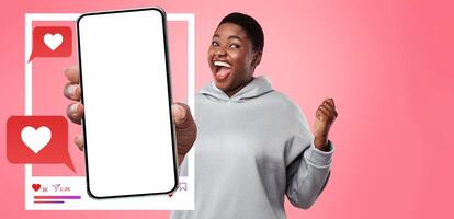 An enthusiastic influencer holds a smartphone, displaying a blank screen for social media interactions. With a vibrant background, she appears ready to engage online and share content. photo
