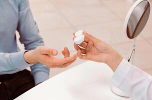 A patient is handed a contact lens case by an eye care professional in a bright clinic. The professional demonstrates proper lens handling to ensure safe usage. photo