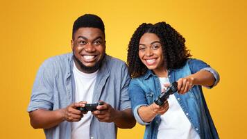 Two friends share a joyful moment playing games, smiling broadly as they engage with their controllers. The vibrant yellow background adds to the fun atmosphere of their gaming experience. photo