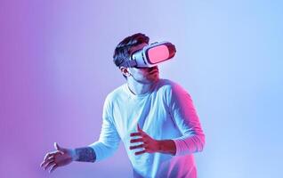 A man is fully immersed in a virtual reality experience, wearing a VR headset. He displays a surprised expression as he interacts with an unseen digital environment. photo