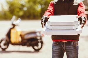 Pizza Delivery. Unrecognizable Courier Offering Pizzas Boxes To Camera Standing Outdoor. Cropped, Empty Space photo