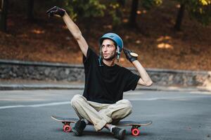 The guy is sitting on a logboard. Rest after skateboarding. photo