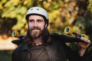 Portrait of a bearded guy with a skateboard, a longboard in his hands. photo