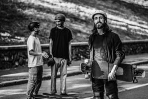 A group of guys ride longboards. Black and white portrait of a skateboarder. photo