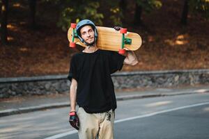 Portrait of a guy with a longboard on his shoulder. Skateboarding in summer. photo