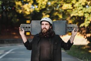 A guy with a longboard smokes a cigarette. A combination of sports and lifestyle. photo