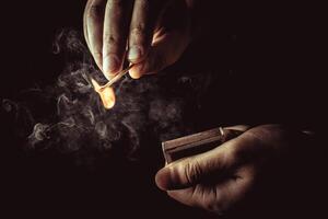 Playing with fire. A burning match in a man's hand on a black background. photo