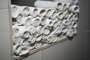Rolled white towels neatly arranged on a shelf in a soothing bathroom setting photo