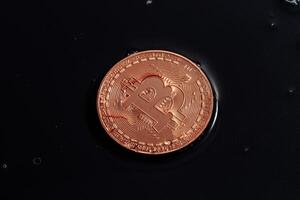 Bitcoin on black background. Bitcoin laundering with water. photo