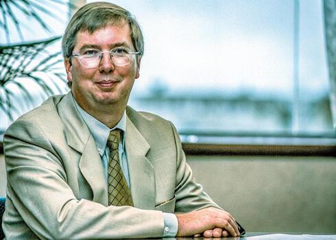 a man in a suit and tie sitting at a desk photo