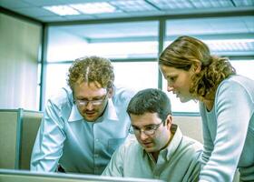 three people looking at a computer screen photo